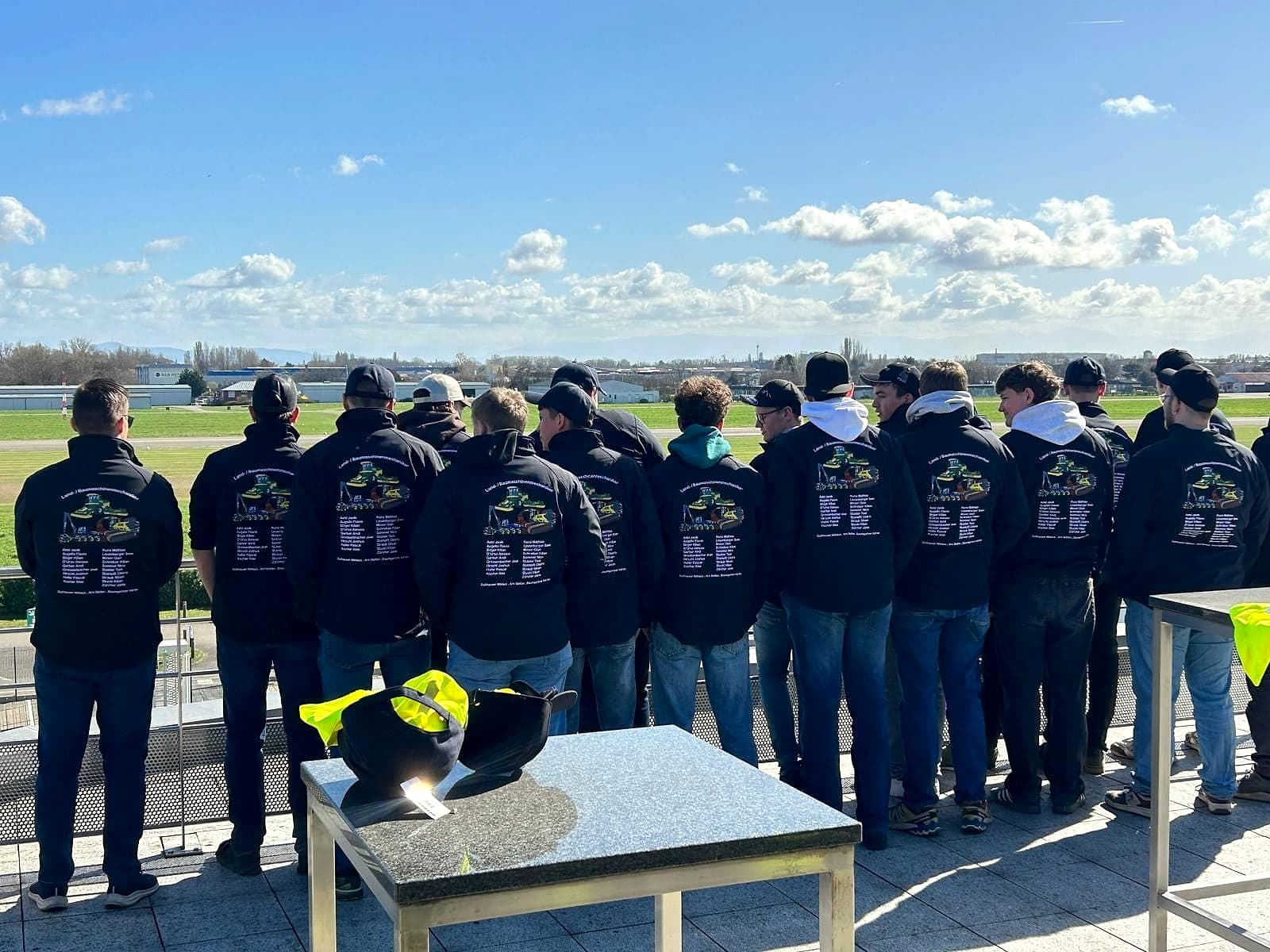 Gruppe von hinten in schwarzen Hoodies mit gesticktem Rückenmotiv und Namen